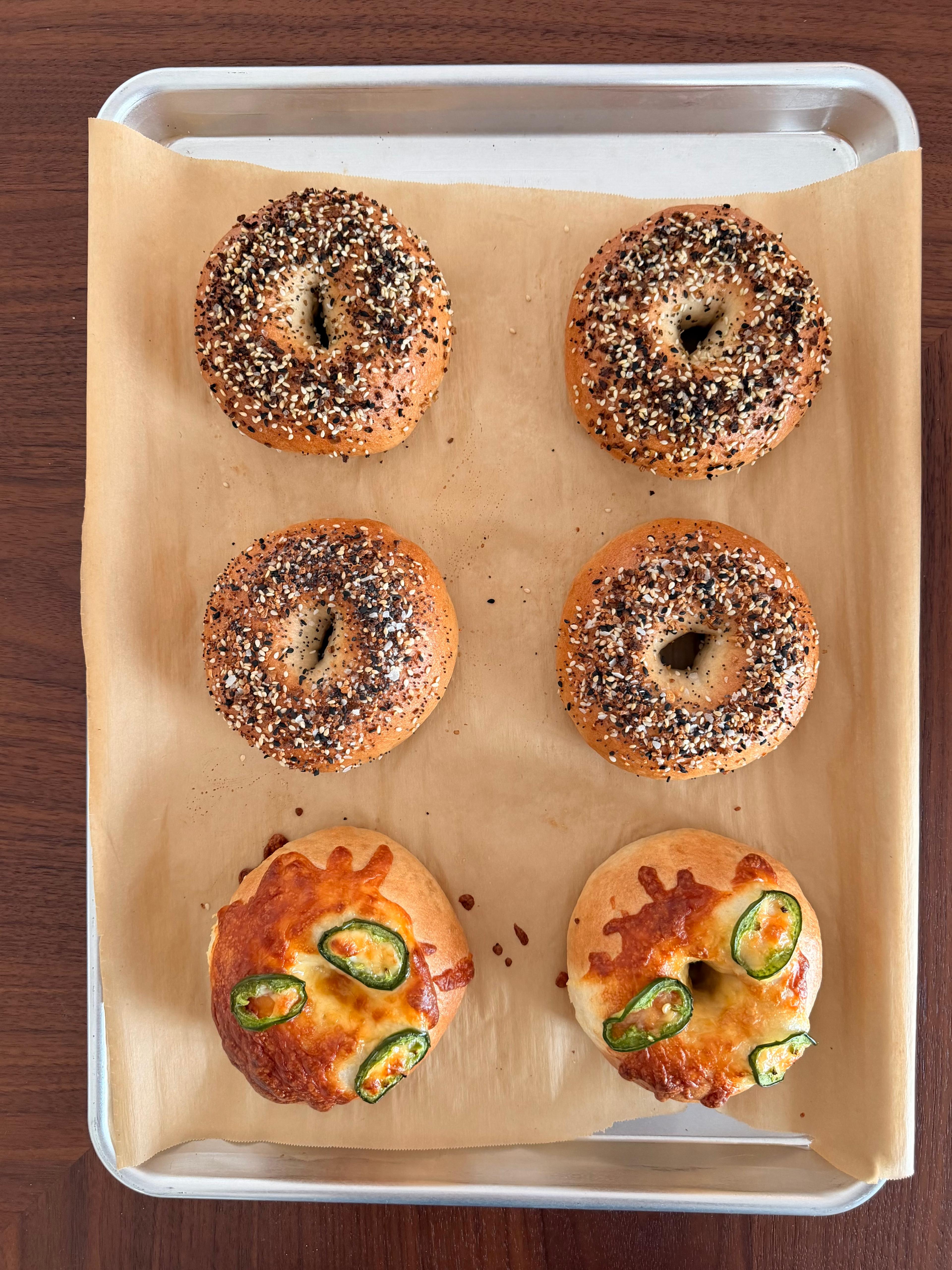 Bagels with different toppings on a baking tray.