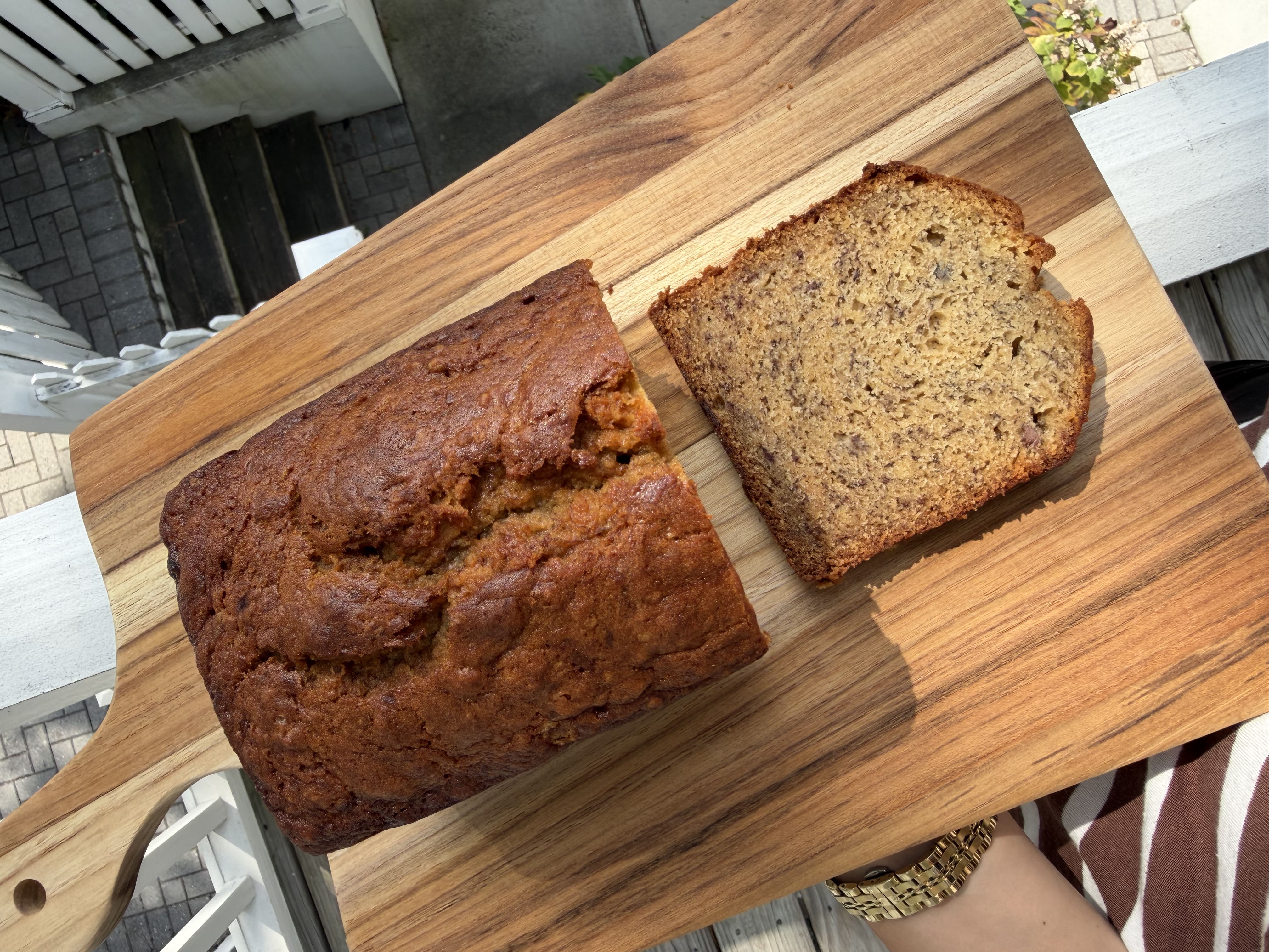 A banana bread on a cutting board with soft sunlight shining on the crispy top.